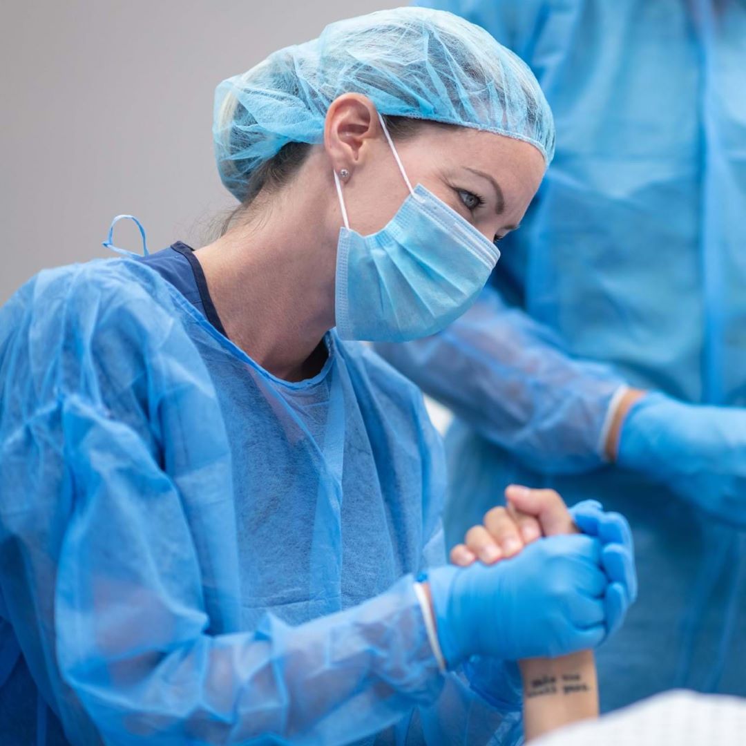 Medical professional in surgical attire holding patient's hand
