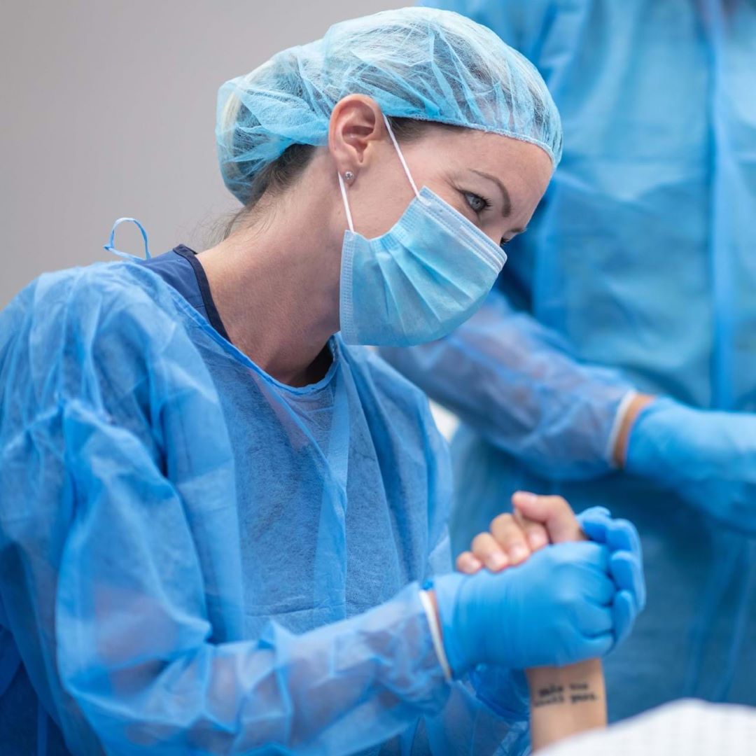 Medical professional in surgical attire holding patient's hand